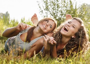 two girlfriends lying down on grass